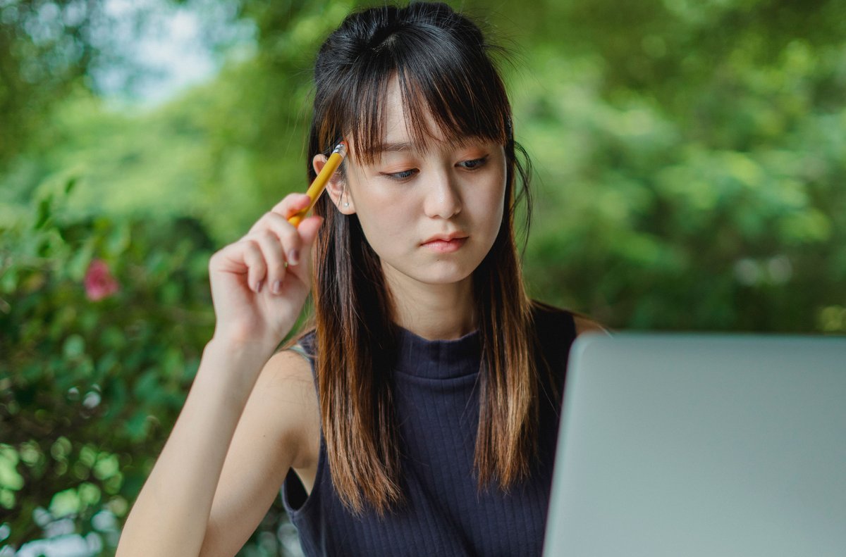 考えごとをしながらノートパソコンに向かう女性