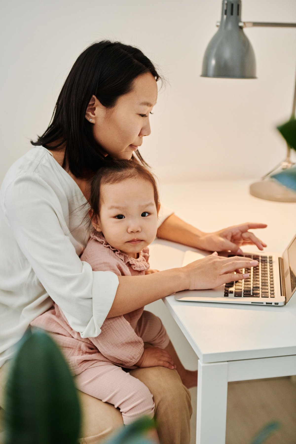 子どもを抱いてパソコンに向かう母親